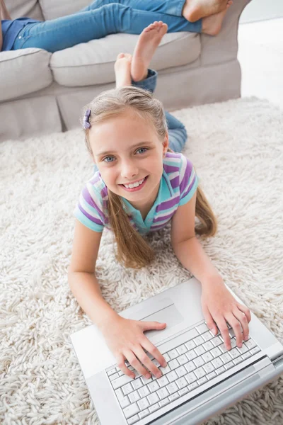 Chica usando el ordenador portátil mientras está acostado en la alfombra —  Fotos de Stock