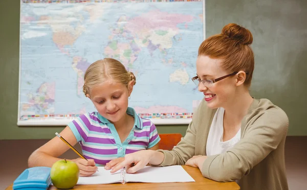 Leraar bijstaan meisje met huiswerk in klas — Stockfoto