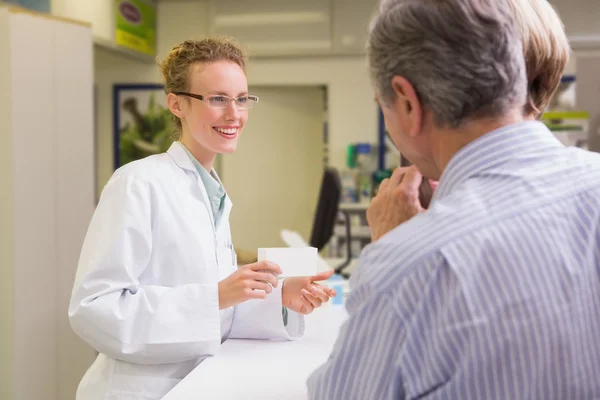 Farmacêutica e seus clientes falando sobre medicação — Fotografia de Stock