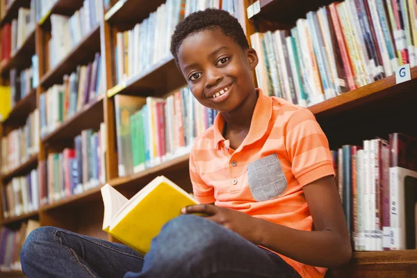 Bonito menino leitura livro na biblioteca — Fotografia de Stock