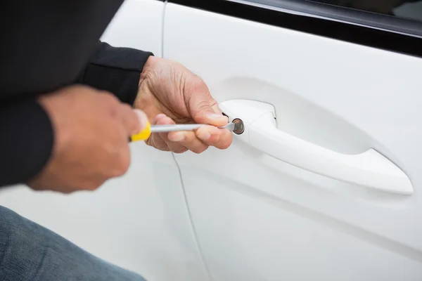 Thief breaking into car with screwdriver — Stock Photo, Image