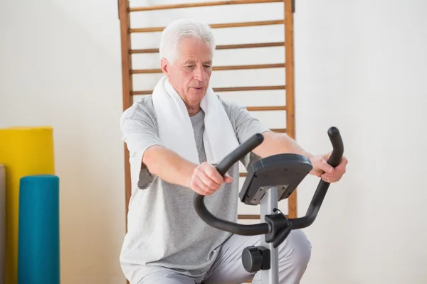 Senior man doing exercise bike — Stock Photo, Image