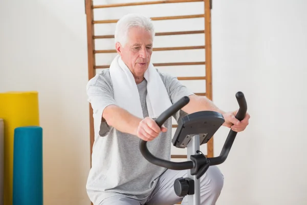 Homem sênior fazendo bicicleta de exercício — Fotografia de Stock