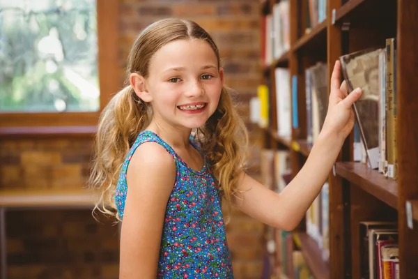 Linda niña seleccionando libro en la biblioteca — Foto de Stock