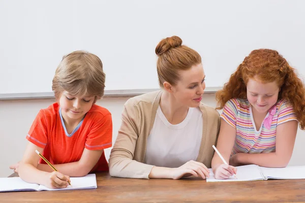 Teacher and pupils working at desk together — Stock Photo, Image