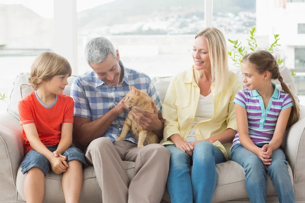 Familjen sitter med katt på soffa — Stockfoto