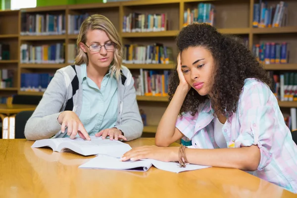 Student, uzyskanie pomocy od nauczyciela w bibliotece — Zdjęcie stockowe