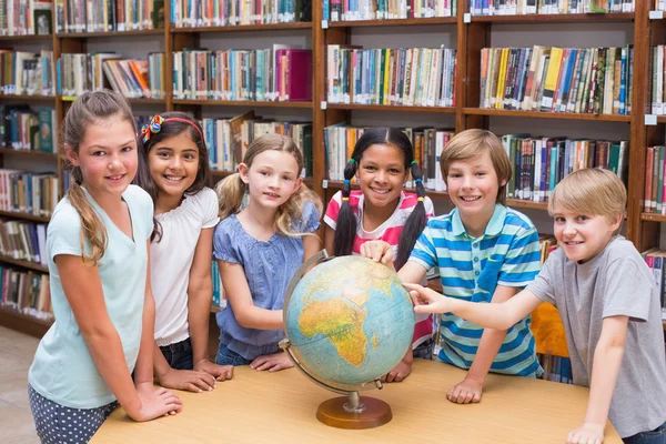 Pupilas bonitos olhando globo na biblioteca — Fotografia de Stock