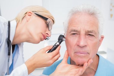 Doctor examining senior patients ear clipart