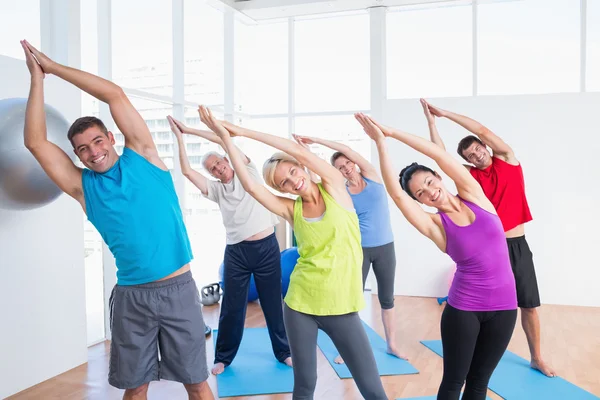 Gente feliz haciendo ejercicio de estiramiento en clase de yoga —  Fotos de Stock