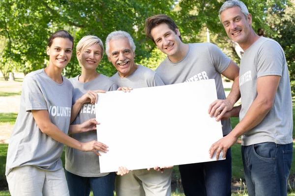 Vrijwilligers en gelukkige familie houden een blanco — Stockfoto