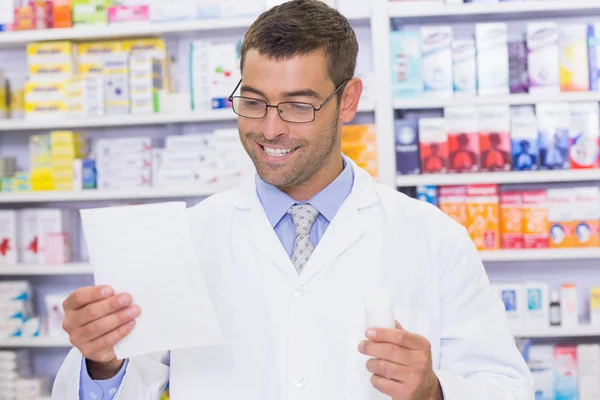Happy pharmacist looking at prescription — Stock Photo, Image