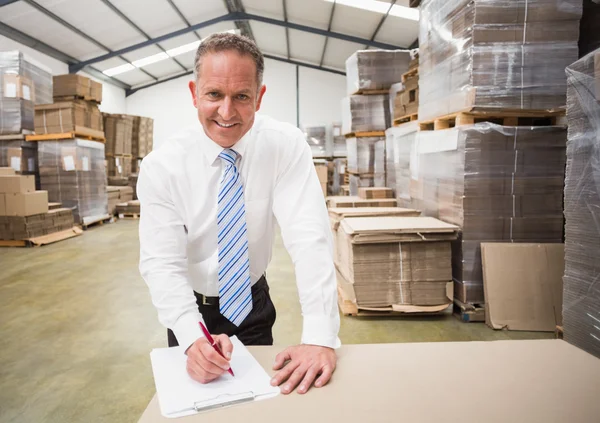 Smiling boss writing on clipboard — Stock Photo, Image