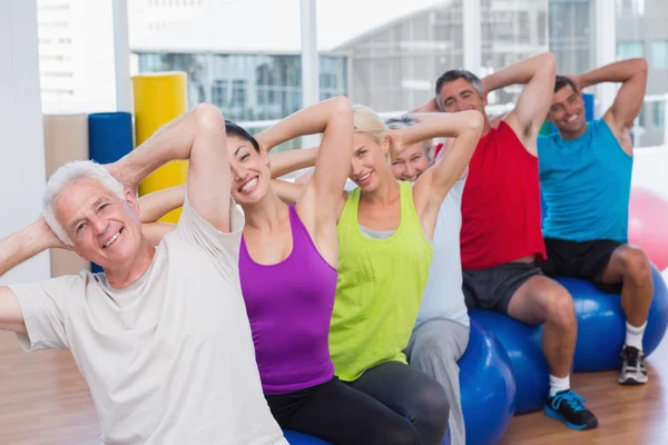 Persone su palle di fitness che esercitano in classe di palestra — Foto Stock