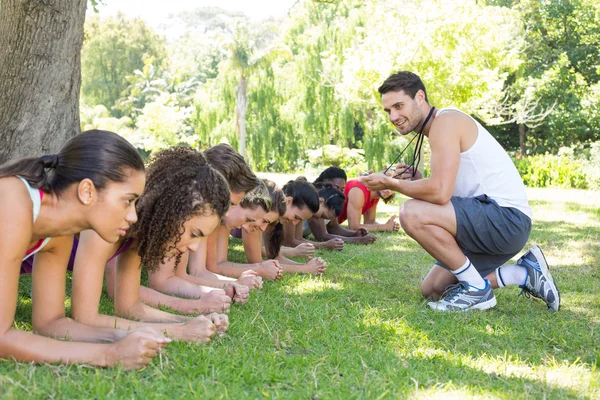 Fitness groep planking in park met coach — Stockfoto