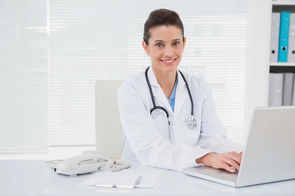 Médico sorrindo usando laptop — Fotografia de Stock