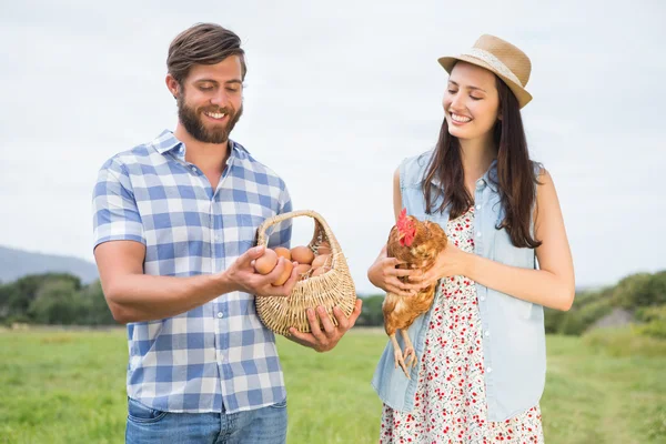 Mutlu çiftçiler holding tavuk ve yumurta — Stok fotoğraf