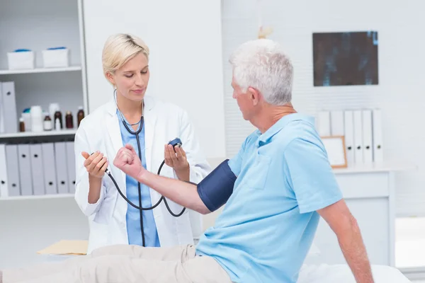 Médico verificando a pressão arterial masculina sênior — Fotografia de Stock