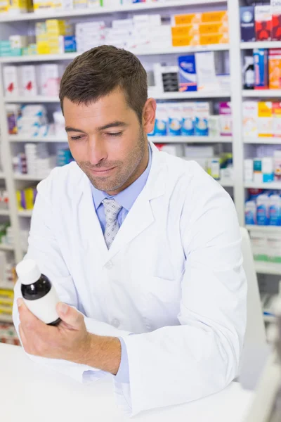 Handsome pharmacist lokking at medicines bottle — Stock Photo, Image