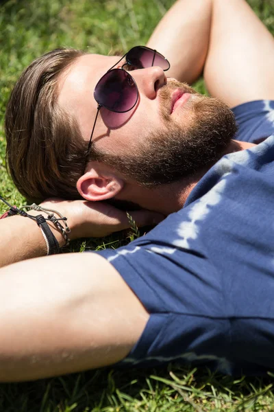 Красавчик-хипстер лежит на траве — стоковое фото