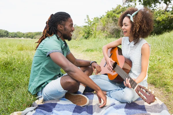 Молодая пара на пикнике играет на гитаре — стоковое фото