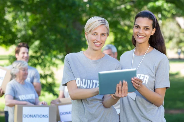 Happy volunteer friends using tablet pc — Stock Photo, Image