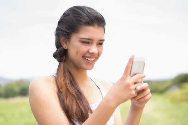 Pretty brunette texting in the park — Stock Photo, Image