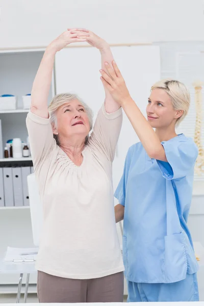 Verpleegkundige meewerkende patiënt in het verhogen van de armen — Stockfoto