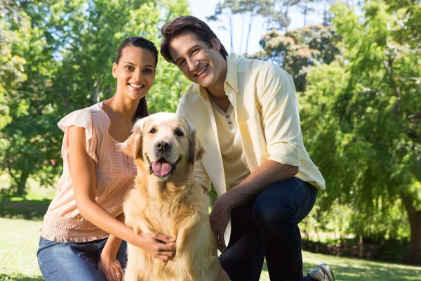 Casal feliz com seu cão de estimação no parque — Fotografia de Stock