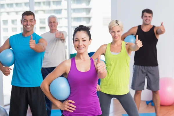 Instruktör med klass gestikulerande tummen upp på gym — Stockfoto