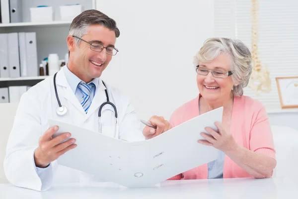 Médico e paciente olhando para relatórios em arquivo — Fotografia de Stock