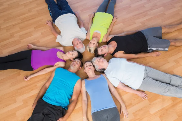 Mensen liggen in cirkel op hardhouten vloer op sportschool — Stockfoto