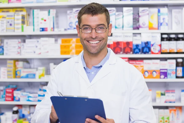 Happy pharmacist writing on clipboard — Stock Photo, Image