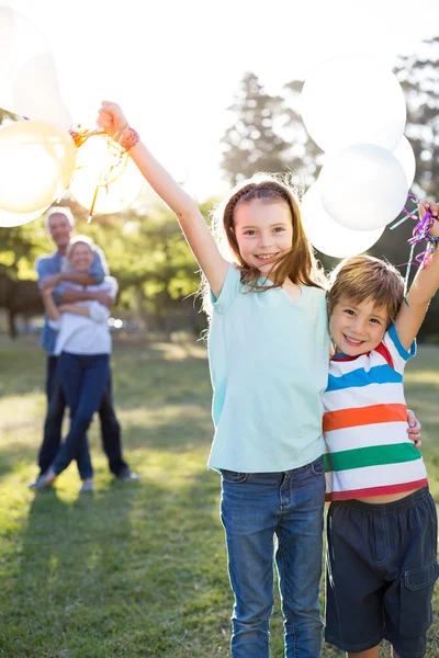 Glückliche Geschwister mit Luftballons im Park — Stockfoto