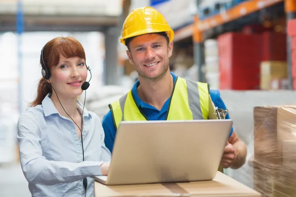 Sorridente donna d'affari che indossa auricolare utilizzando il computer portatile — Foto Stock