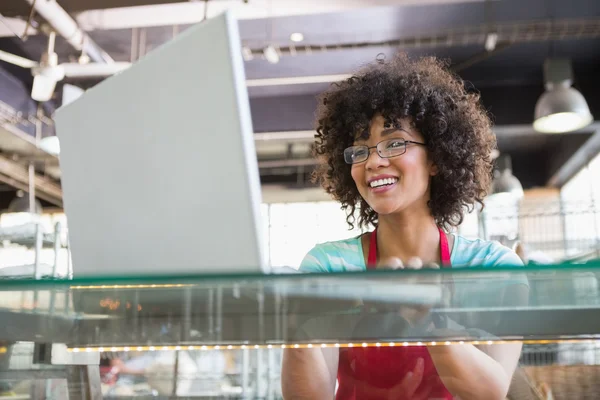 Garçonete sorridente com óculos usando laptop — Fotografia de Stock