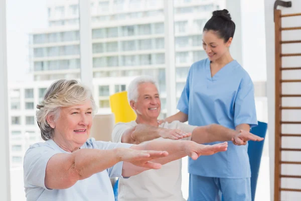 Instructor assisting couple to exercise — Stock Photo, Image