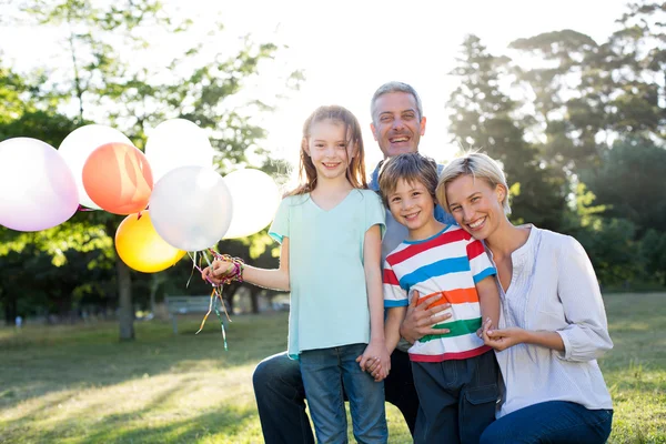 Glückliche Familie hält Luftballons im Park — Stockfoto