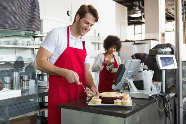 Kellner schneidet Kuchen auf, Kellnerin hinter ihm — Stockfoto