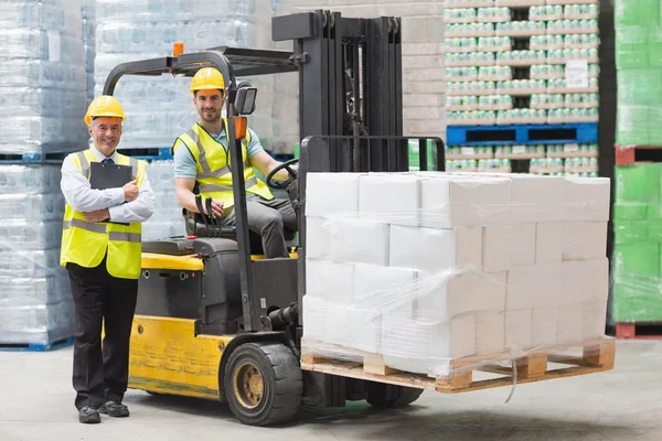 Macchina del carrello elevatore di funzionamento del driver accanto al suo responsabile — Foto Stock