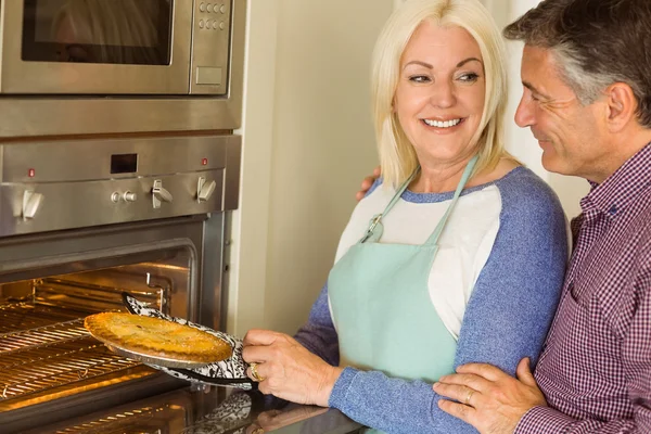 Vrouw die verse taart uit oven — Stockfoto