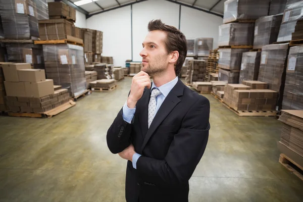 Magazijnbeheerder denken met hand op kin — Stockfoto