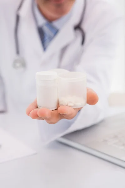 Médico segurando pílulas garrafas — Fotografia de Stock