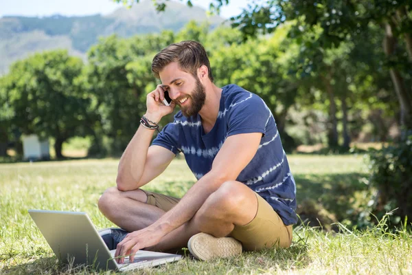 Yakışıklı hipster parkta dizüstü bilgisayar kullanarak — Stok fotoğraf