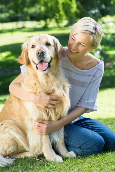 Blonde knuffelen haar hond in het park — Stockfoto