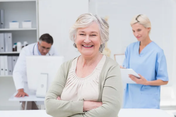 Paciente sonriendo mientras el médico y la enfermera trabajan —  Fotos de Stock