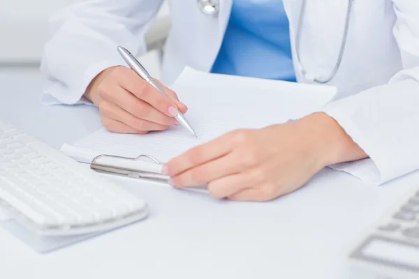 Médico feminino que escreve prescrições à mesa — Fotografia de Stock