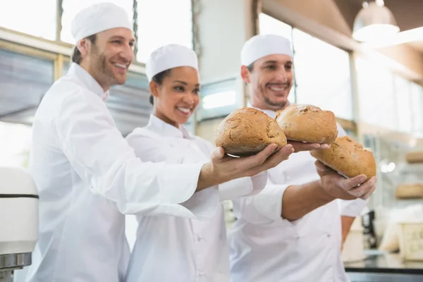 Smiling colleagues showing loaf of bread — Stock Photo, Image