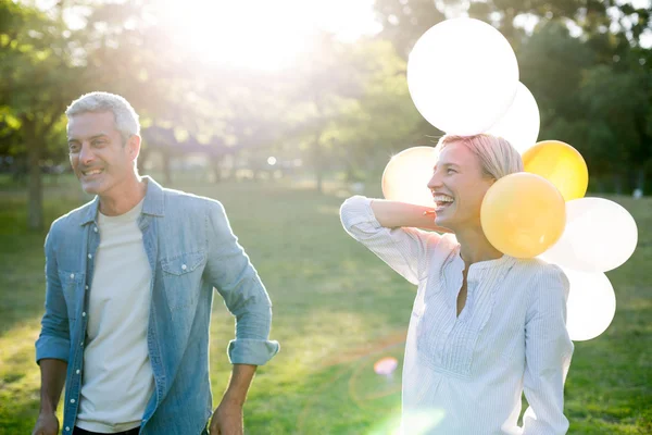 Pareja feliz con globos en el parque — Foto de Stock