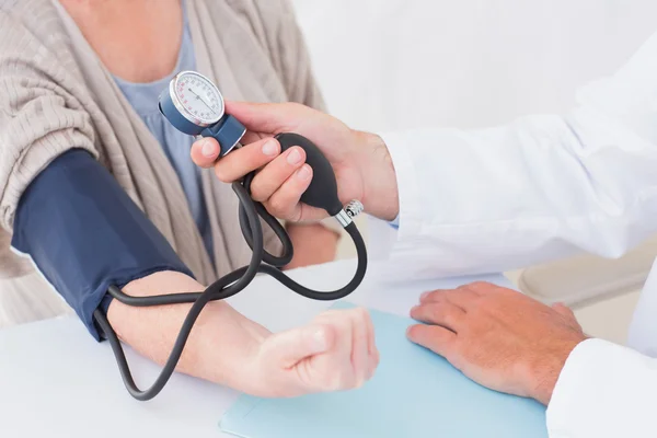 Doctor checking patients blood pressure — Stock Photo, Image